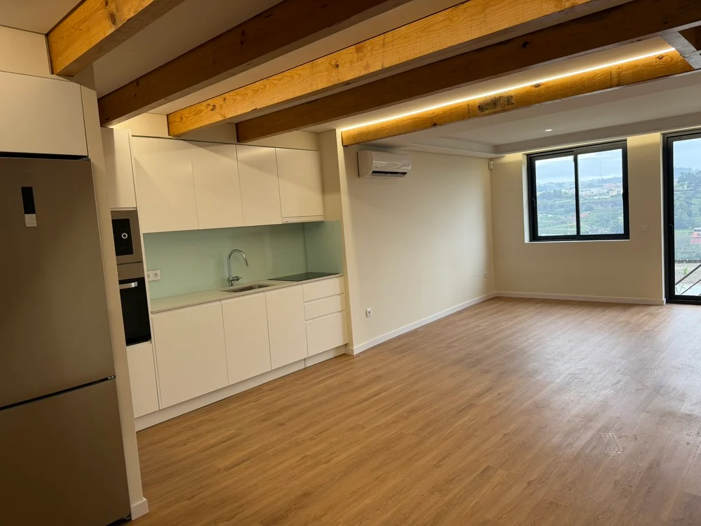 Cozinha branca e zona de estar com vigas de madeira à vista